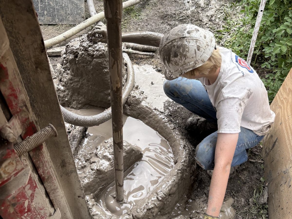 Earth Power technician operating a drill rig in a tight residential side yard